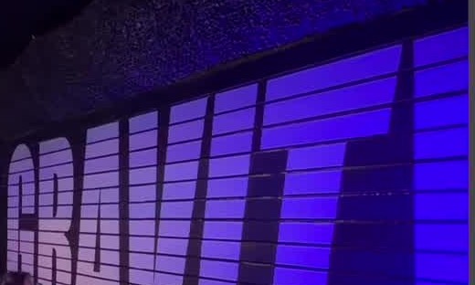 The huge GRAVITY letters painted across a gym wall, lit violet